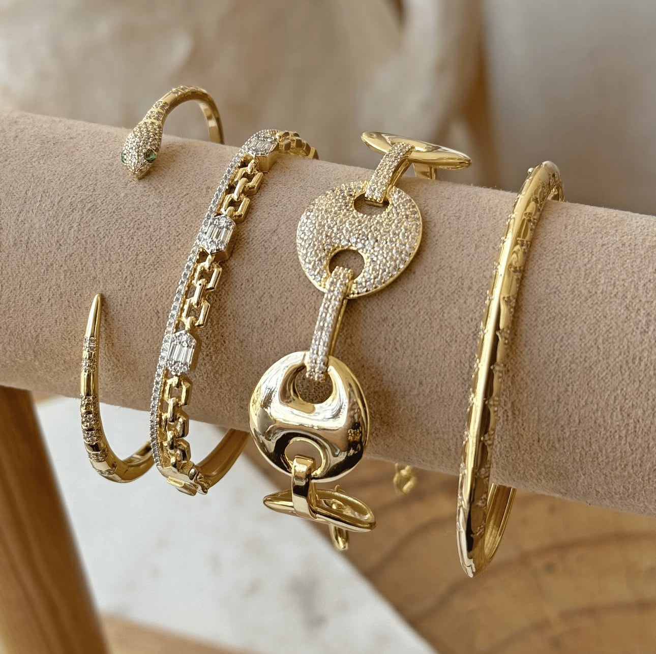 Gold bracelets on a person's wrist with a neutral background