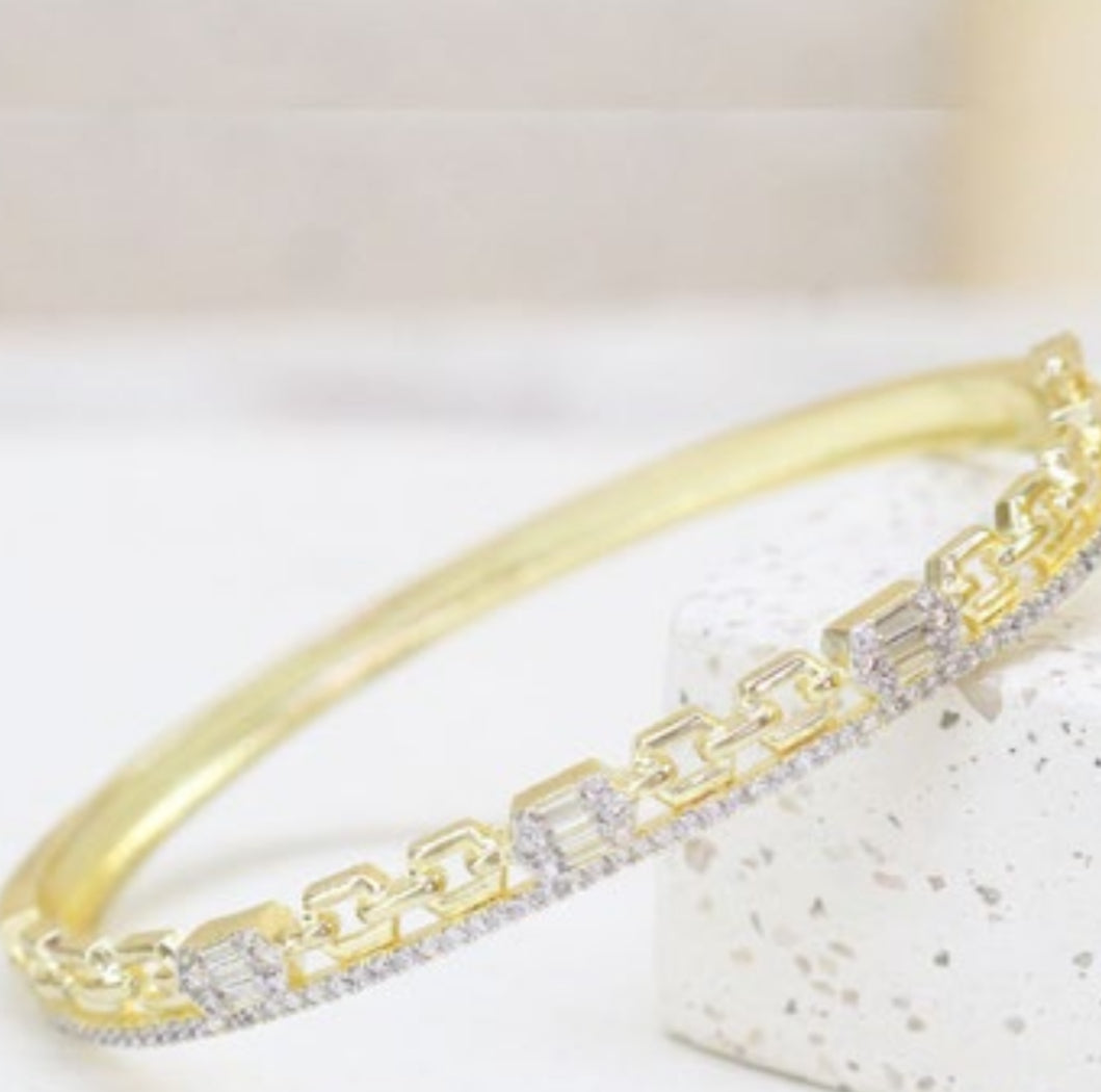 Gold bling bracelet with clear zircon stones on a light background