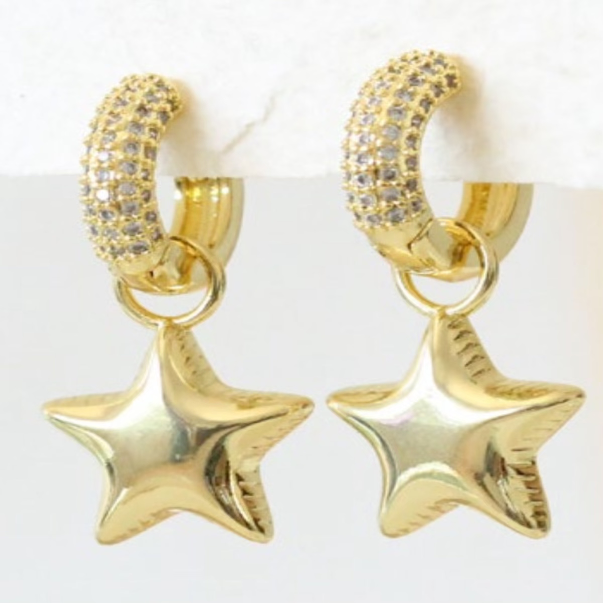 Gold hoop earrings with cubic zirconia pave huggies and dangling gold star charms"