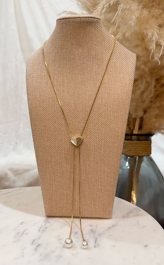 Gold necklace with a heart-shaped pendant on a mannequin bust.