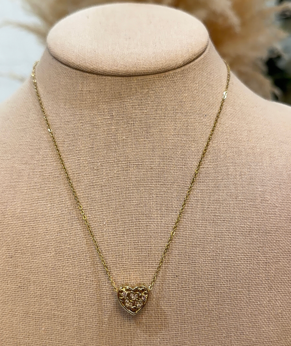 Gold necklace with a heart-shaped pendant on a beige mannequin bust.