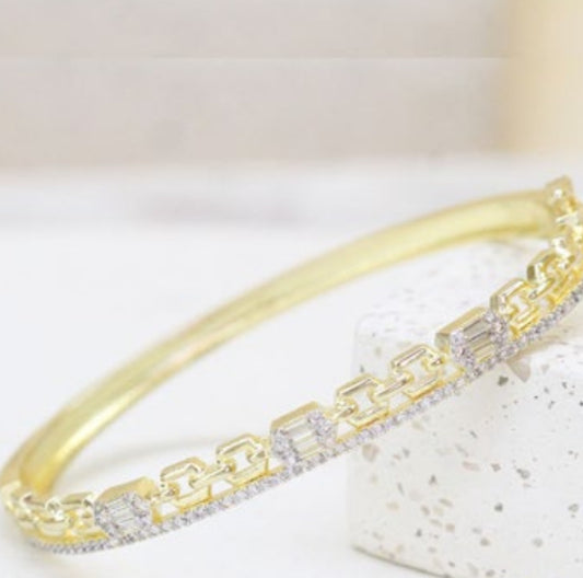 Gold bling bracelet with clear zircon stones on a light background