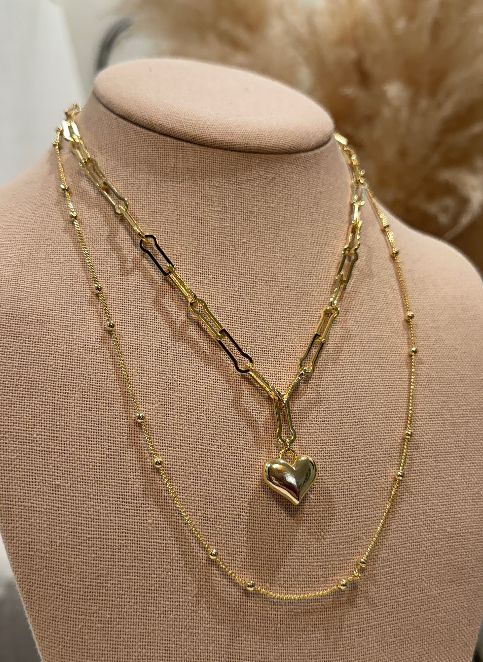 Gold necklace with a heart pendant on a mannequin bust.