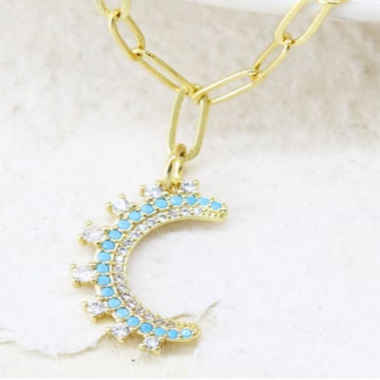 Gold crescent moon necklace with turquoise enamel and cubic zirconia on a gold link chain.