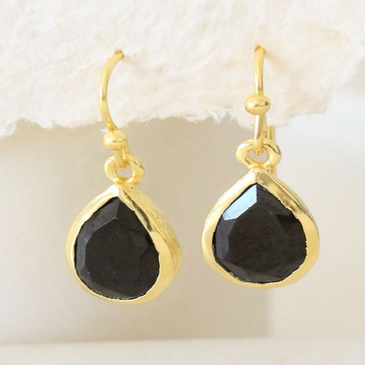 Gold teardrop earrings with faceted black onyx stones on a white background