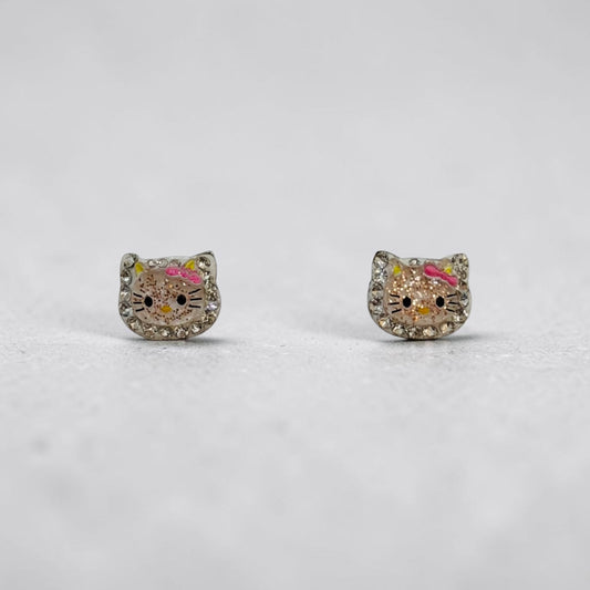 A pair of silver stud earrings shaped like Hello Kitty's face, embellished with clear rhinestones and featuring pink and yellow enamel details, set against a light gray background.