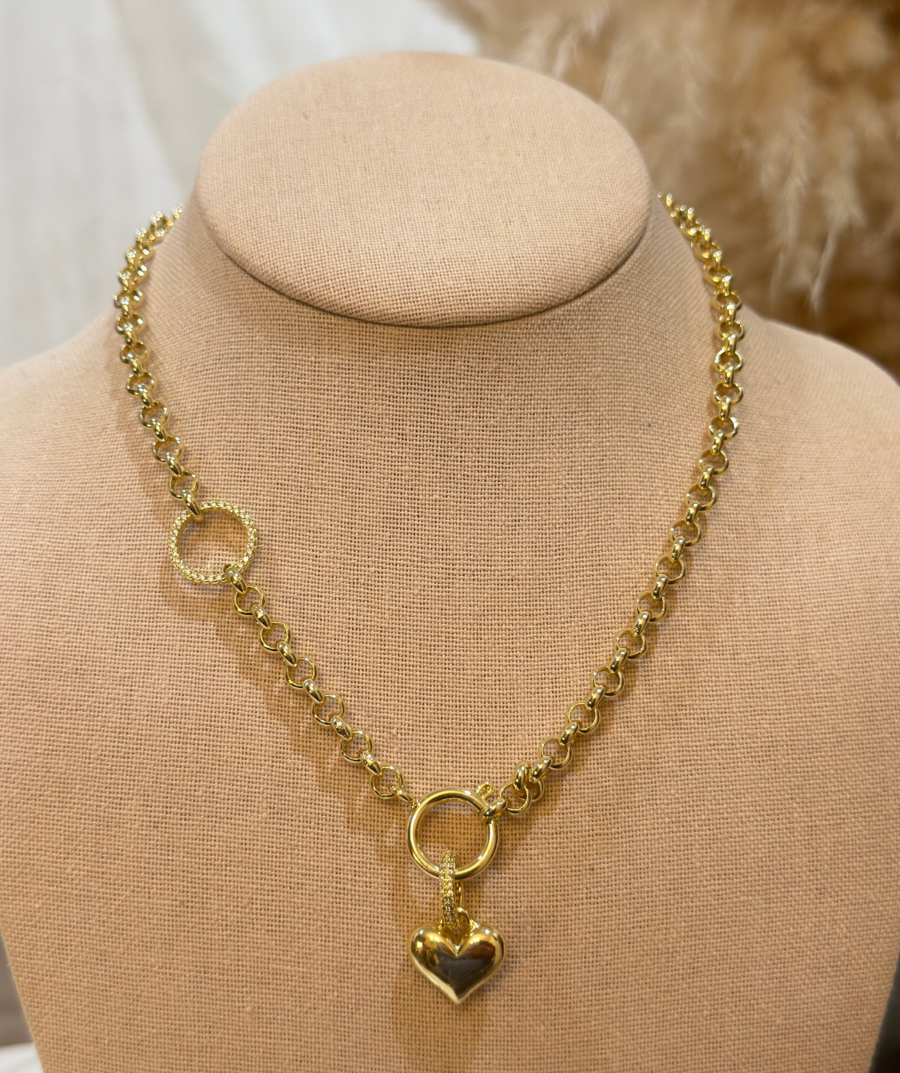 Gold chain necklace with a heart pendant on a beige mannequin bust.