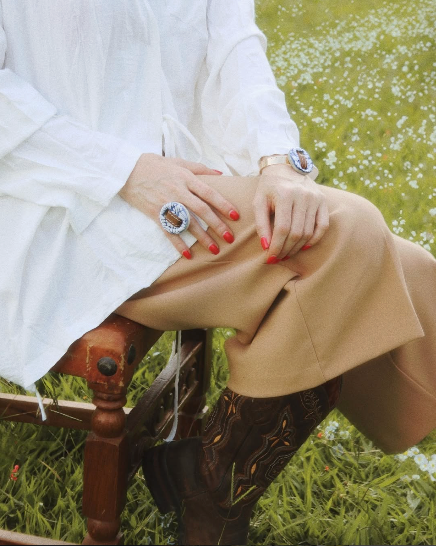Person wearing a white shirt, beige pants, and brown boots with a ring on a grassy background talavera clay big clay statement ring belt ring leather jewelry 