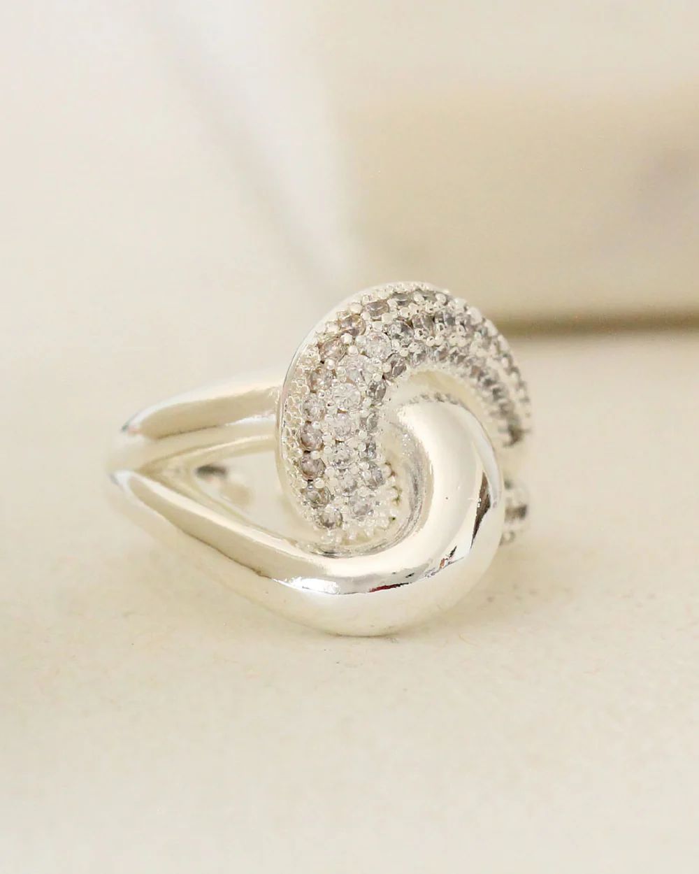 Silver ring with diamond zirconia accents on a light beige background