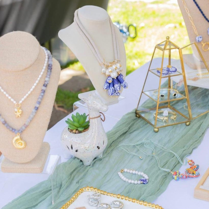 Jewelry display on a table outdoors with various necklaces and accessories.
