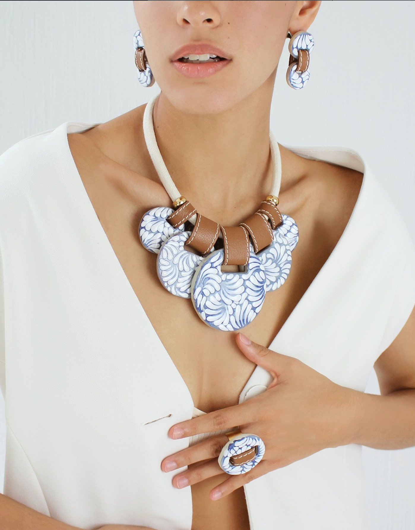 Woman wearing a luis valerio clay talavera oaxaxa mexico handcrafted statement necklace and earrings on a white background